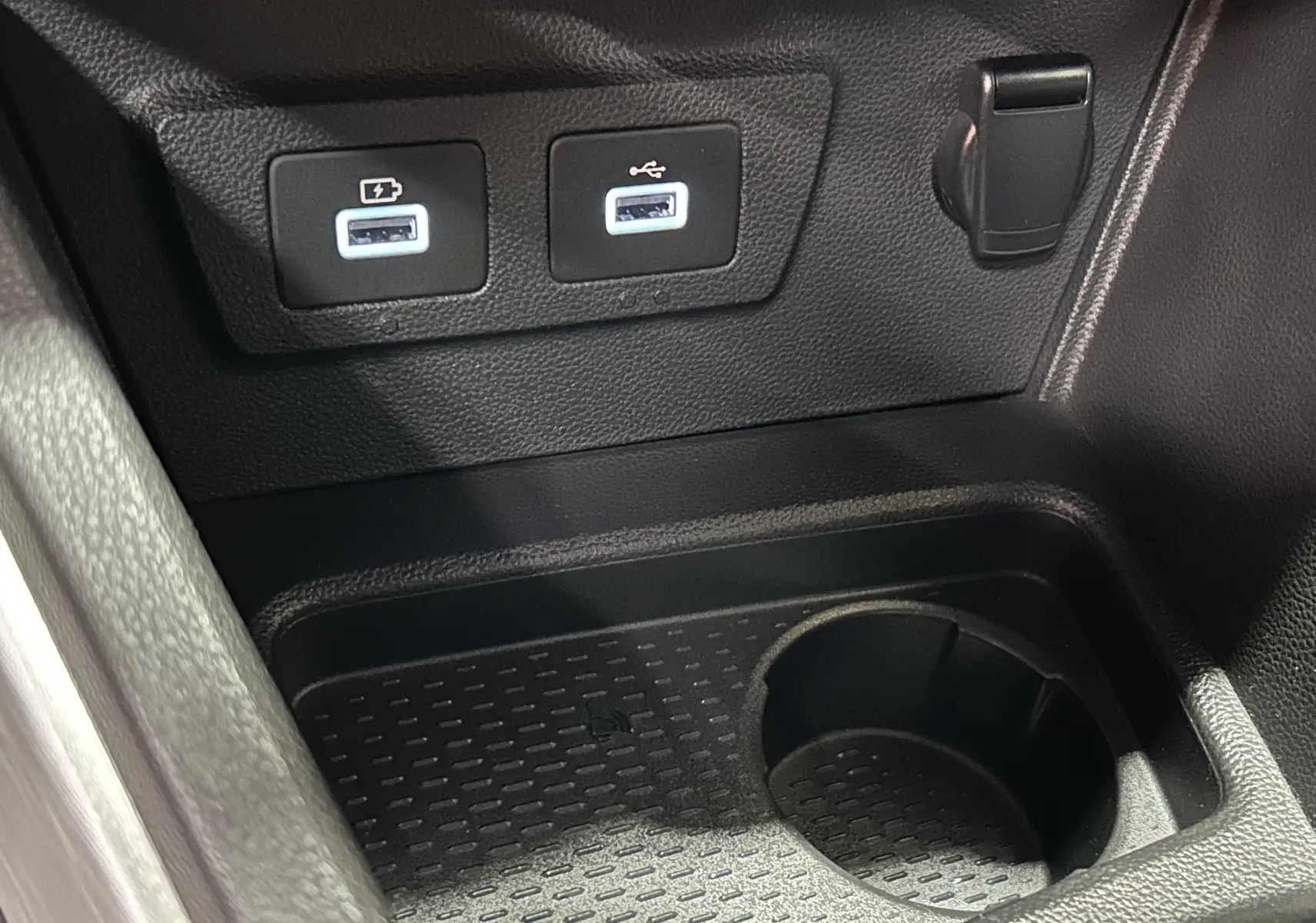 Gros plan sur la console centrale du Dacia Duster 2022 montrant deux ports USB et un porte-gobelet noir.