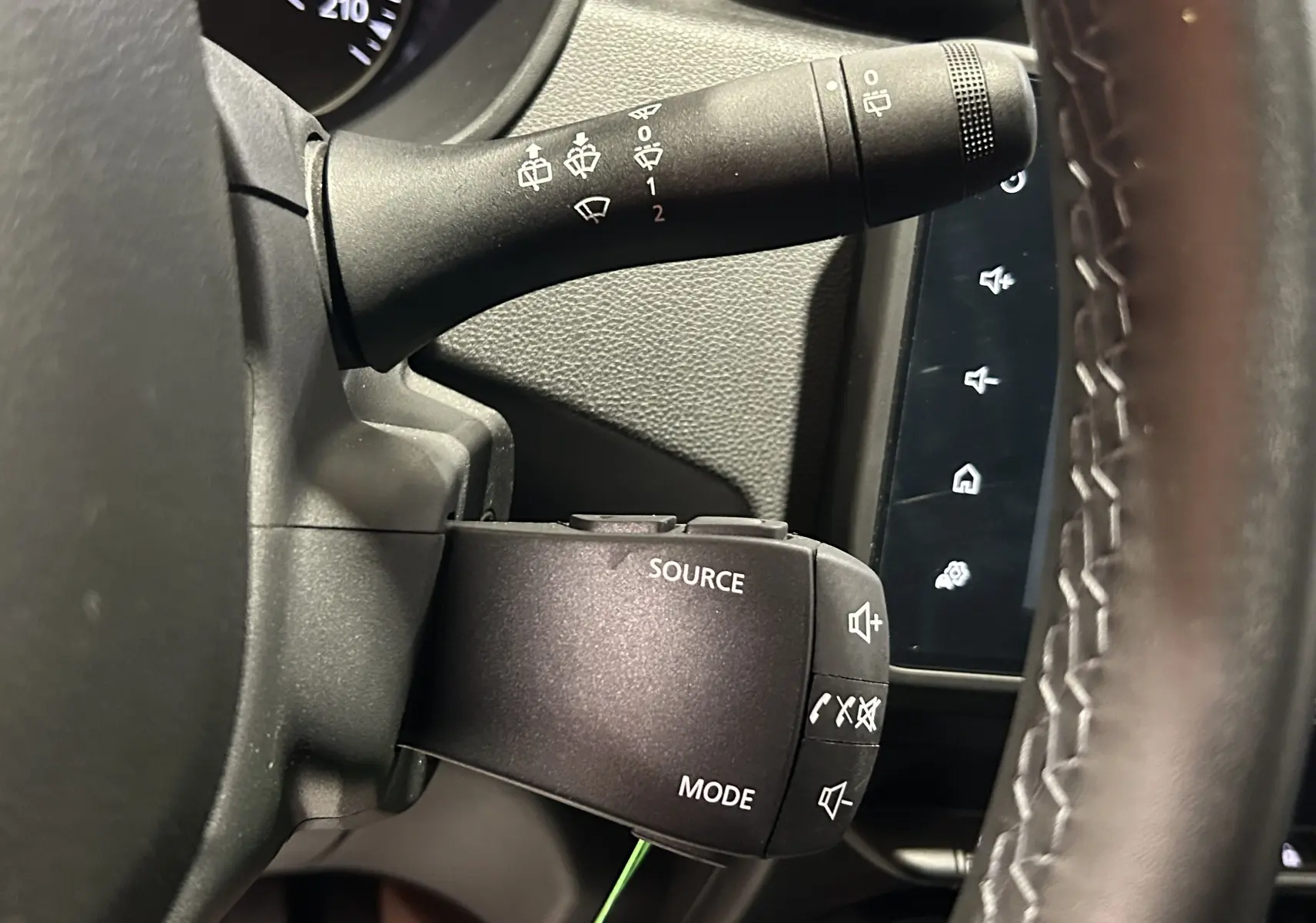 Gros plan sur la commande audio au volant du Dacia Duster 2022, avec tableau de bord et commandes d’essuie-glace visibles.