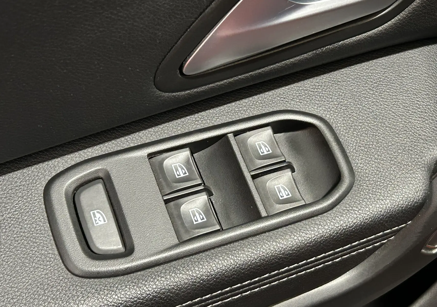 Gros plan sur les commandes électriques des vitres côté conducteur du Dacia Duster 2022, intérieur noir texturé.