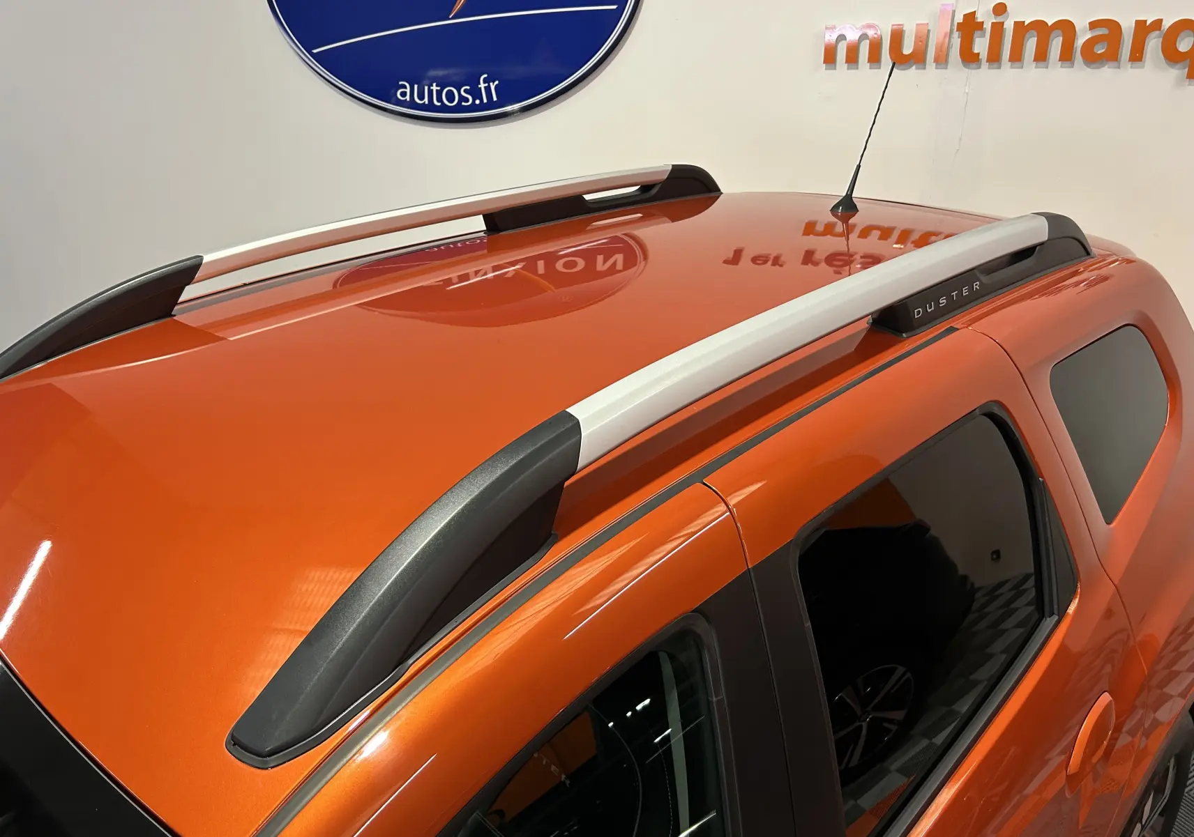 Vue en plongée sur le toit orange Arizona d'un Dacia Duster 2022 avec barres de toit grises et vitres teintées.