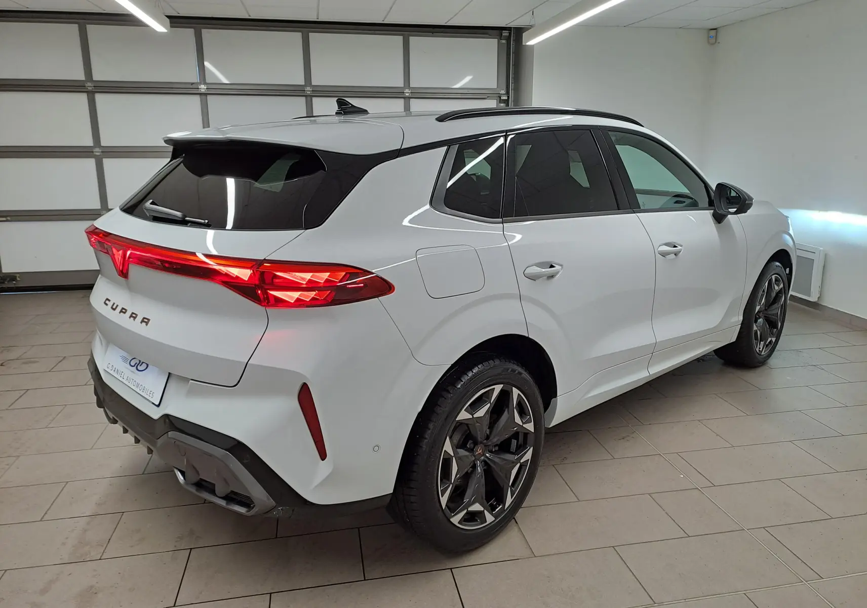 Vue 3/4 arrière droite d'une CUPRA TERRAMAR blanche Nevada avec jantes 19'' Cosmic usinées dans un garage.