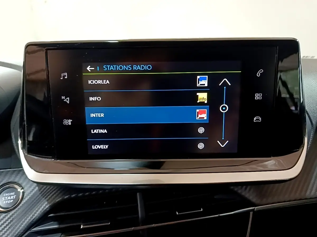 Écran tactile central affichant les stations radio dans l’habitacle d’une Peugeot 208 électrique blanche.