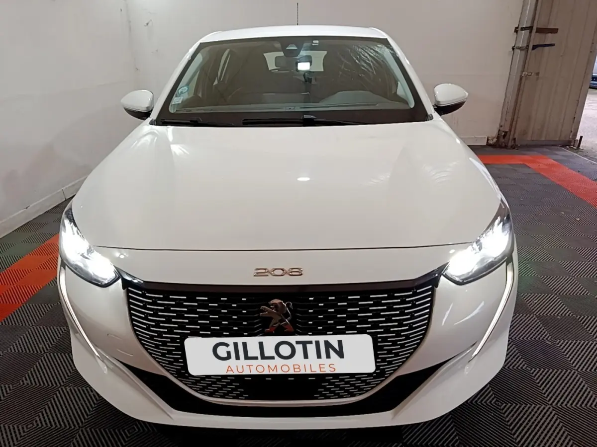 Vue avant d'une Peugeot 208 électrique Active Business blanche avec phares LED allumés et calandre noire distinctive.