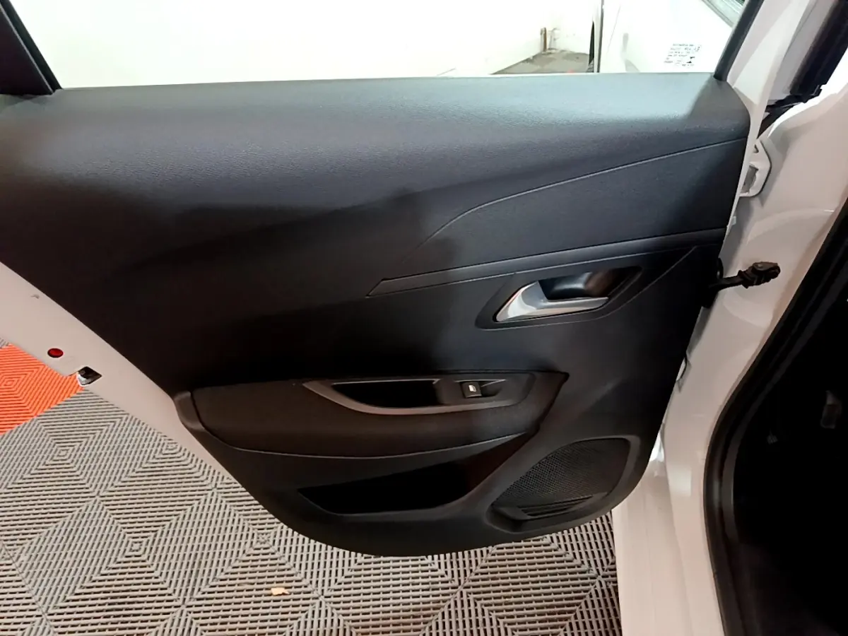 Vue intérieure de la porte arrière droite noire d'une Peugeot 208 électrique blanche, avec poignée et commande de vitre.