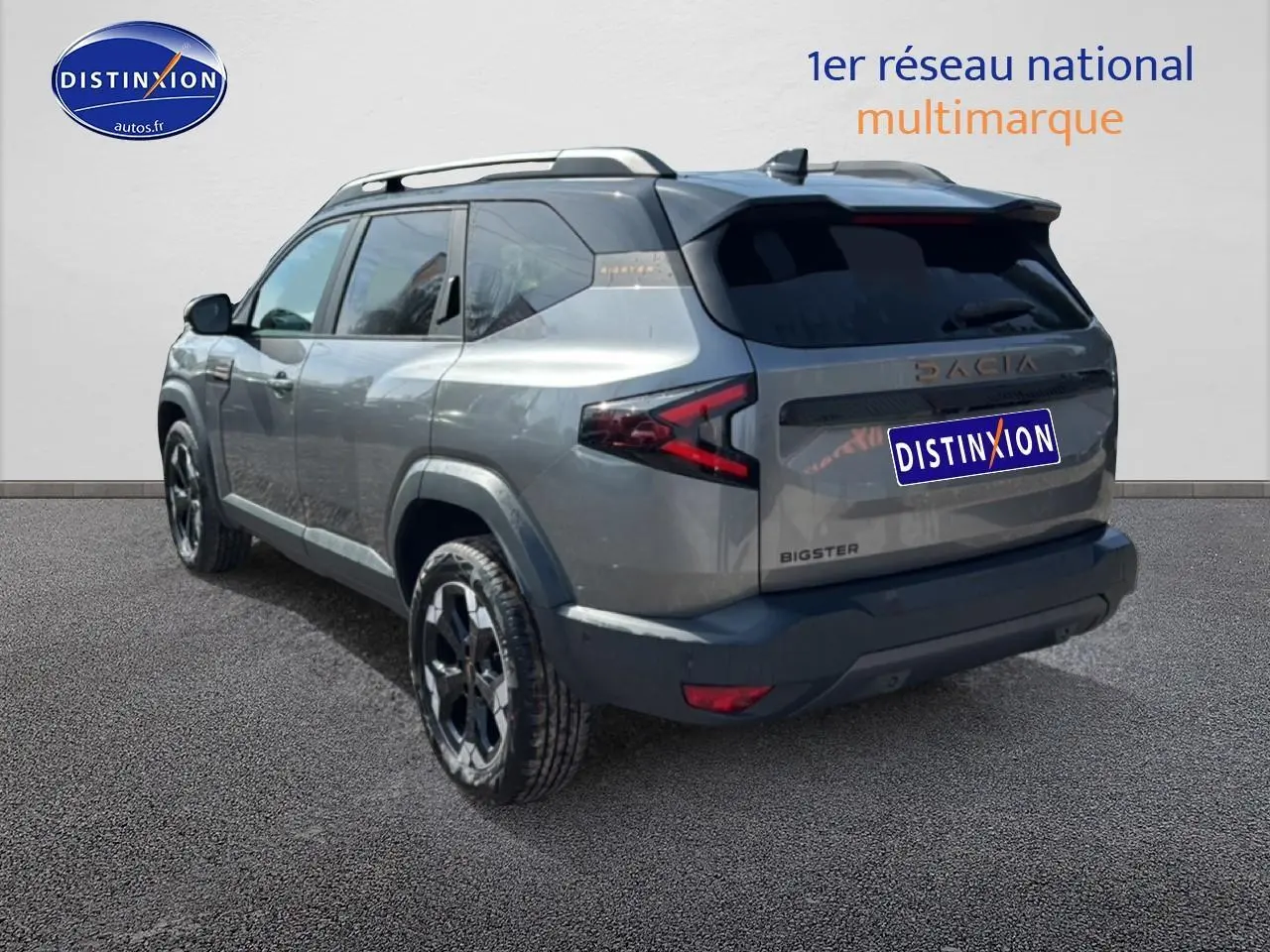 Vue 3/4 arrière droit du Dacia Bigster gris schiste avec barres de toit et jantes alliage noires.
