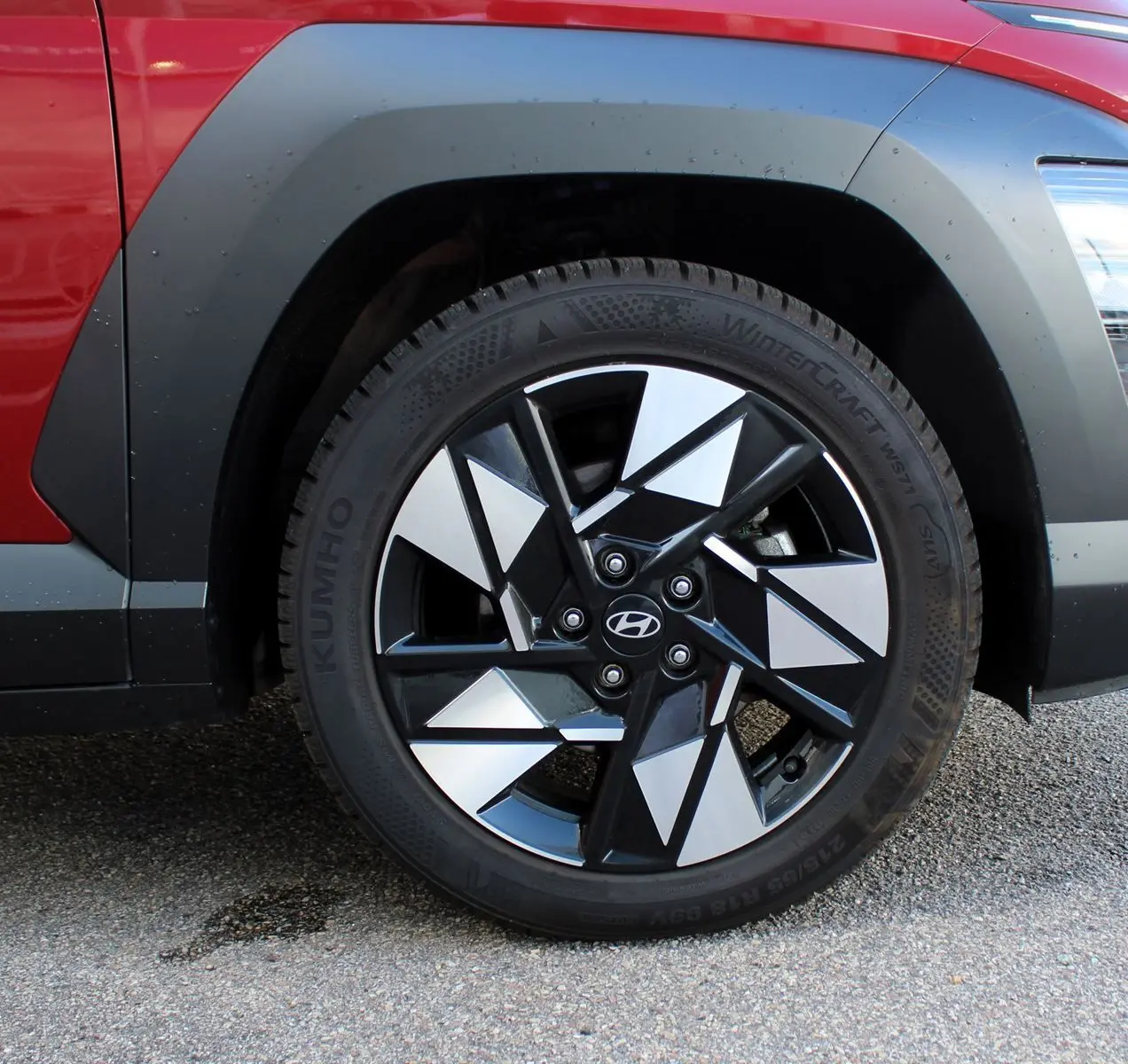 Gros plan sur la roue avant droite du Hyundai Kona 2024 rouge Ultimate avec jante noire et argent à motifs géométriques.