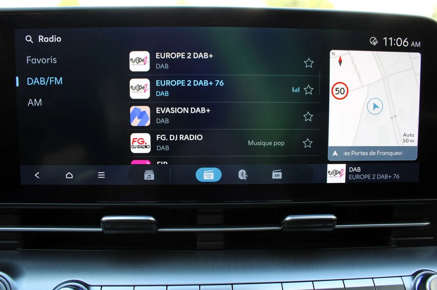 Écran tactile central du Hyundai Kona 2024 affichant la radio DAB/FM et la navigation GPS en intérieur noir.