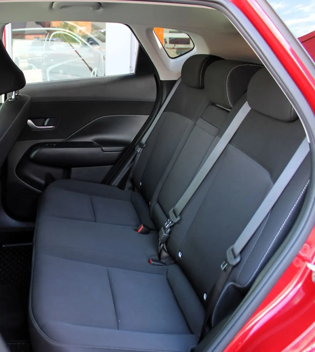 Vue intérieure côté droit des sièges arrière noirs du Hyundai Kona 2024 rouge Ultimate Metal avec ceinture de sécurité.