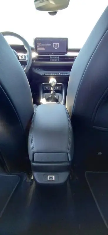 Vue intérieure arrière du Jeep Avenger 2025, montrant la console centrale noire avec levier de vitesse manuel et écran tactile.