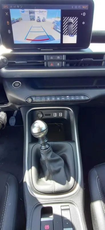 Vue intérieure centrée sur le levier de vitesse manuel et l'écran multimédia du Jeep Avenger blanc 2025, version Summit.