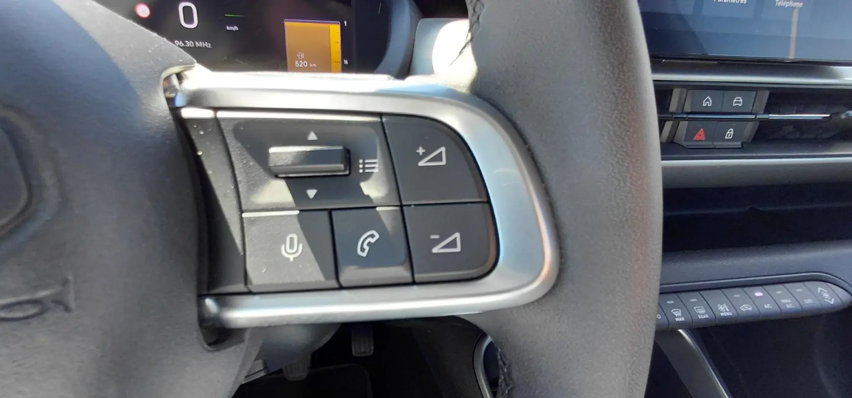 Gros plan sur les commandes au volant côté gauche du Jeep Avenger blanc 2025, avec boutons de volume et appel.