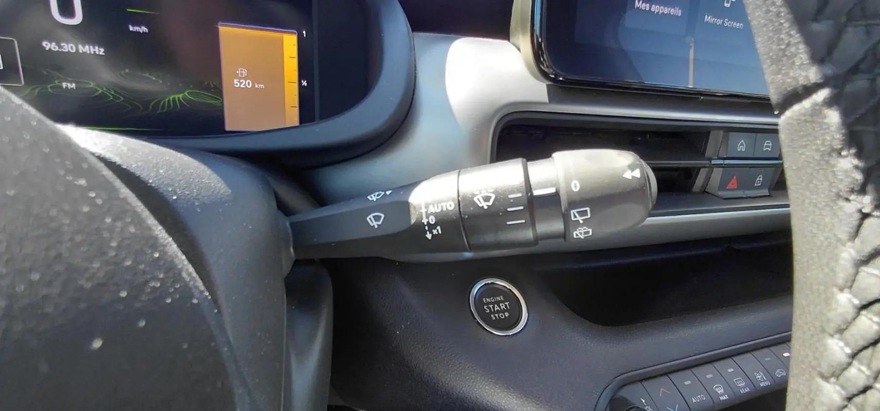 Gros plan intérieur sur la commande d'essuie-glace et le bouton start/stop du Jeep Avenger blanc, tableau de bord digital visible.