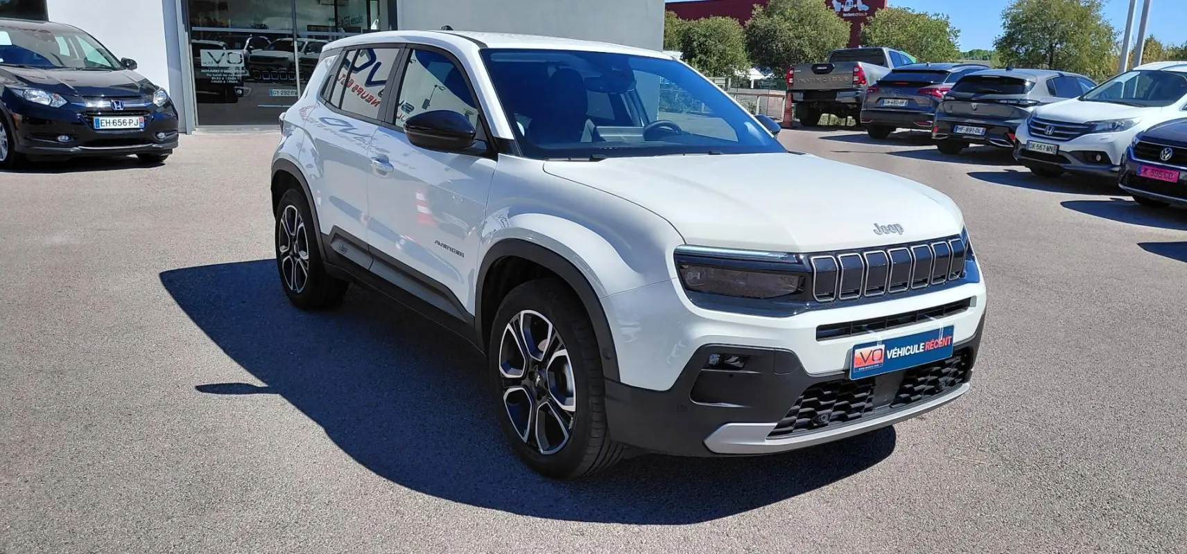 Jeep Avenger blanc en vue 3/4 avant droit, avec calandre noire distinctive et jantes alliage bicolores.