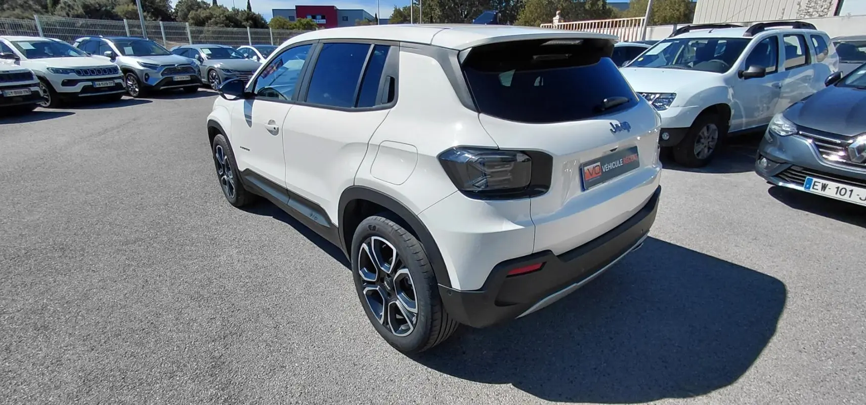 Vue 3/4 arrière droite d’un Jeep Avenger blanc 2025 avec feux arrière fumés et jantes noires distinctives.