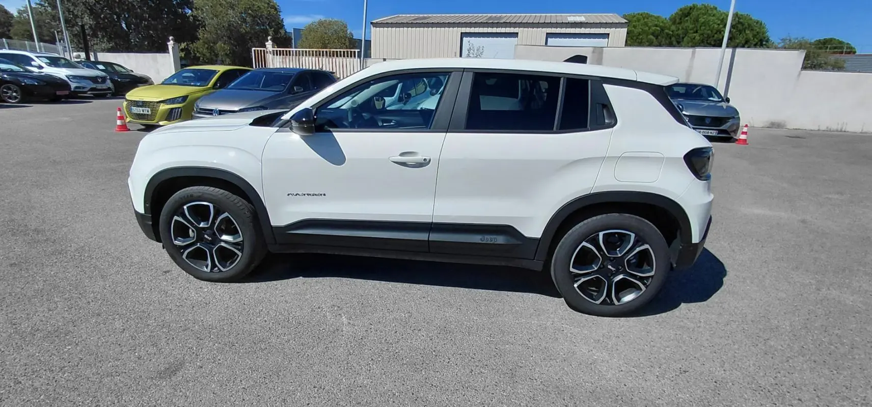 Jeep Avenger blanc vu de profil côté gauche, avec jantes noires et éléments noirs contrastants sur la carrosserie.
