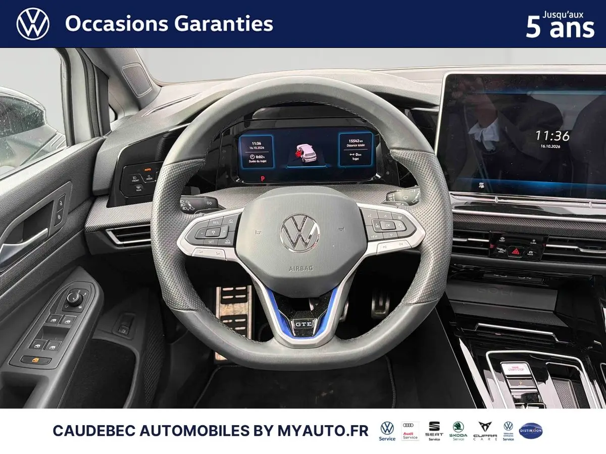 Vue rapprochée du volant sport multifonction en cuir avec logo VW et tableau de bord digital d'une Volkswagen Golf blanche.