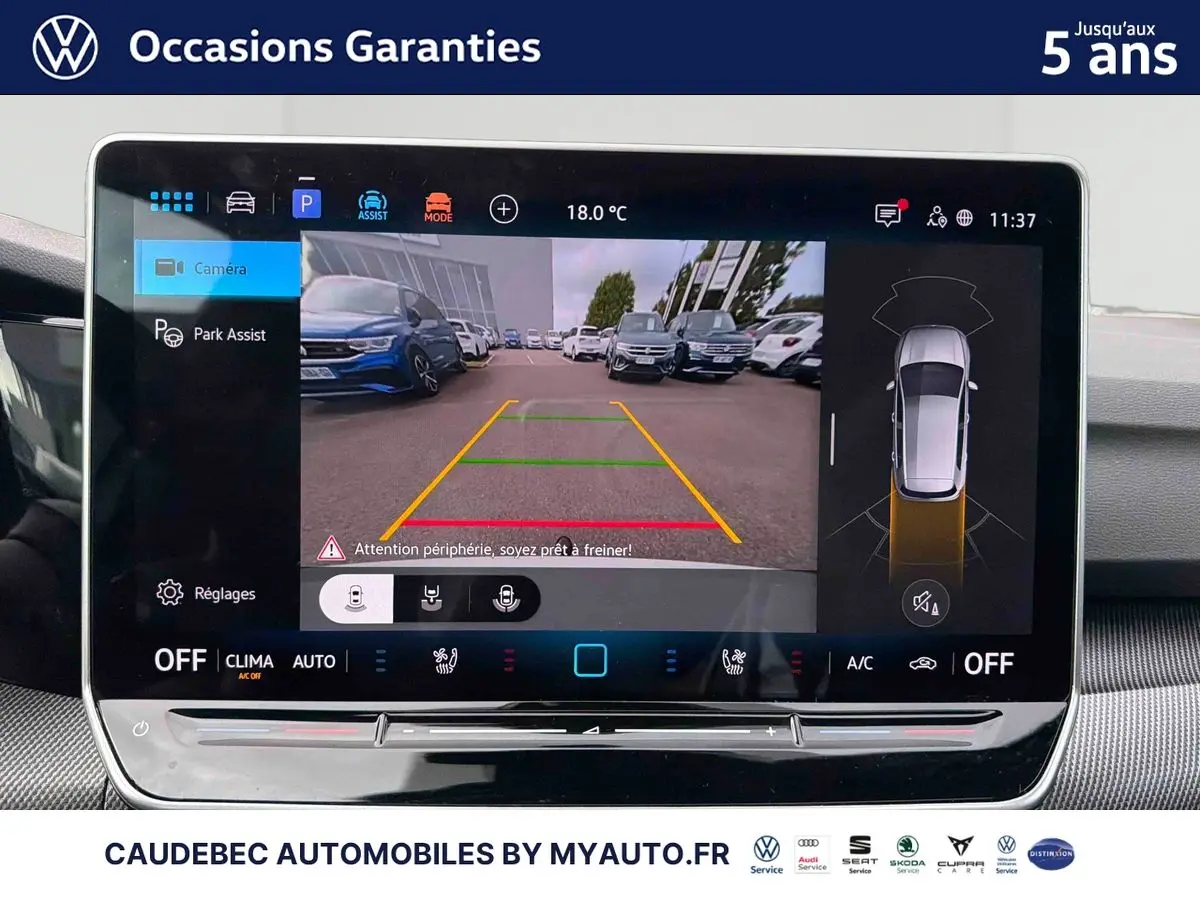 Écran tactile intérieur affichant la caméra de recul et l’aide au stationnement d’une Volkswagen Golf blanche.