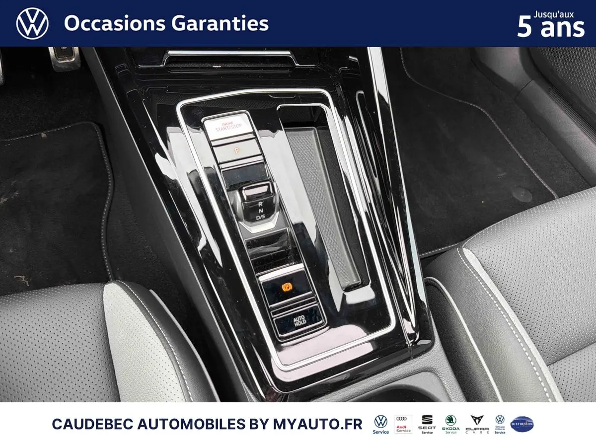 Gros plan sur la console centrale noire brillante avec levier de vitesses et sièges cuir gris clair de la Volkswagen Golf 1.5 eHybrid.