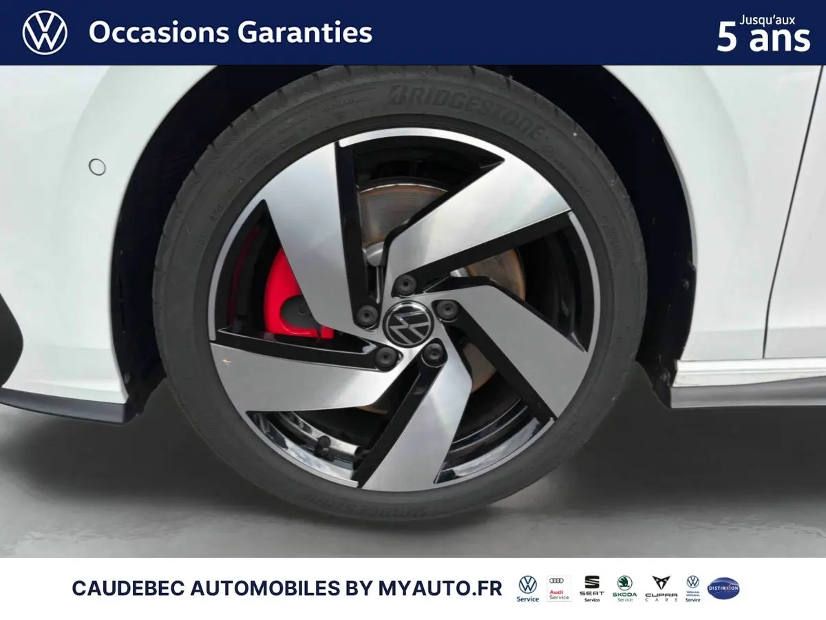Gros plan sur la roue avant gauche blanche d'une Volkswagen Golf 1.5 eHybrid 2025 avec jante alliage bicolore et étrier de frein rouge.