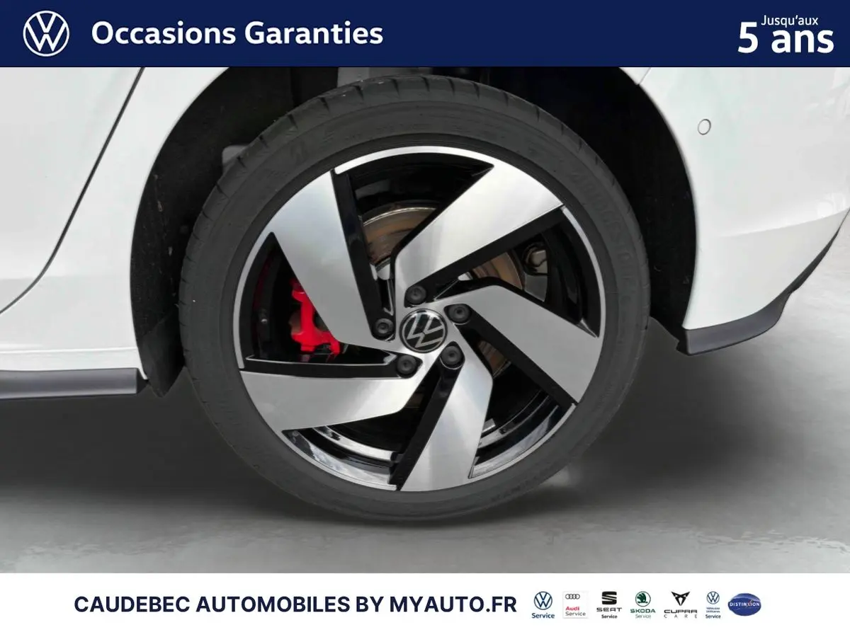 Gros plan sur la roue arrière droite d'une Volkswagen Golf 1.5 eHybrid blanche avec jante alliage noir et argent et étrier de frein rouge visible.