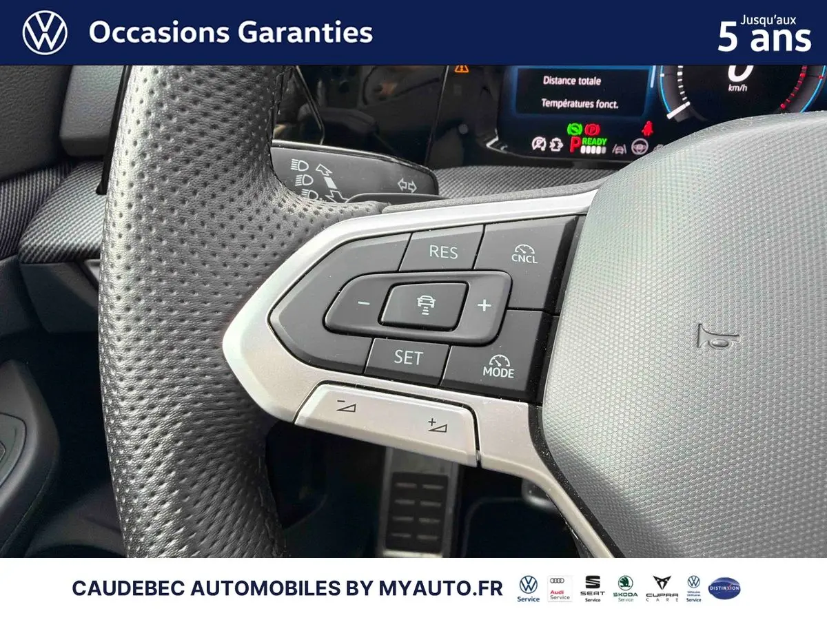 Gros plan sur le volant multifonction en cuir perforé de la Volkswagen Golf 1.5 eHybrid 2025 avec commandes de régulateur adaptatif.