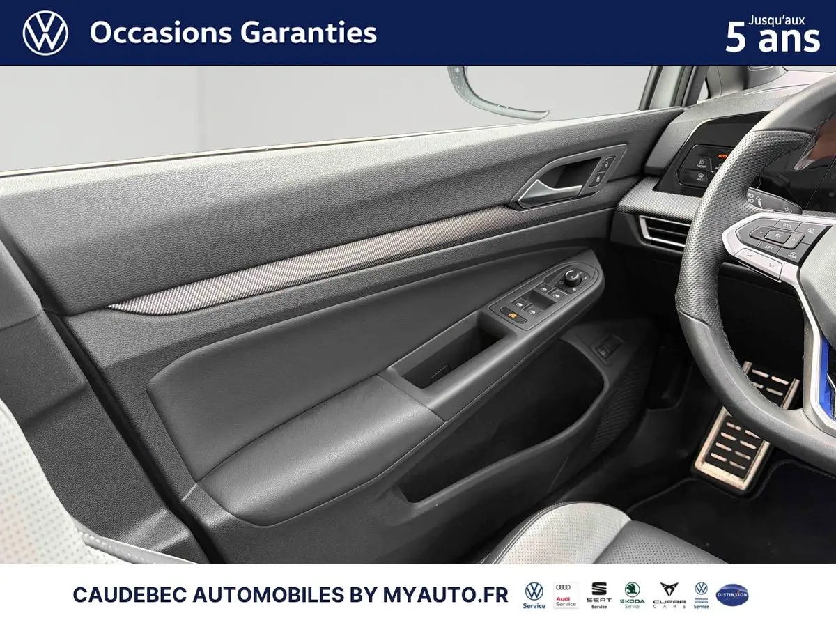 Détail de la porte côté conducteur noire avec commandes électriques dans l’habitacle d’une Volkswagen Golf blanche.