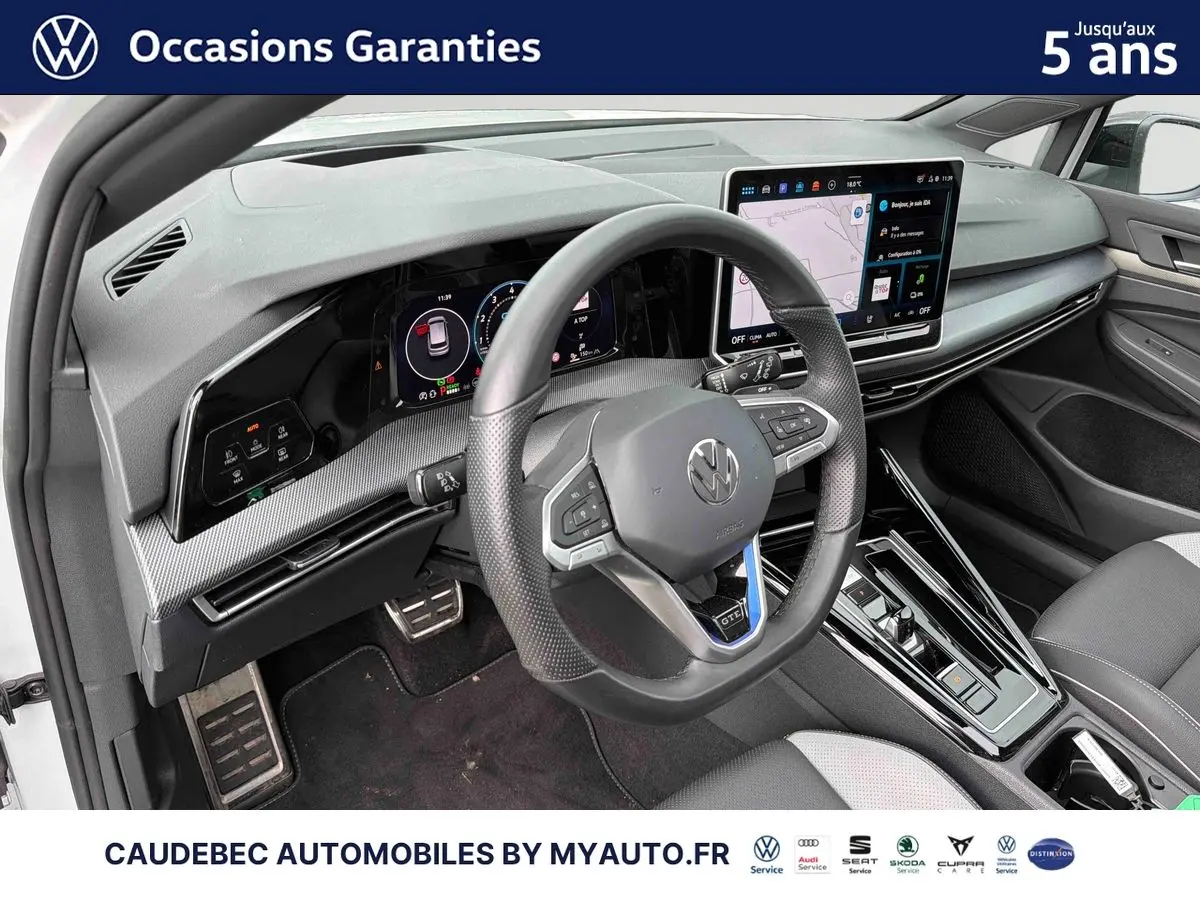 Intérieur de la Volkswagen Golf 1.5 eHybrid 2025, vue côté conducteur sur le volant sport multifonction et l’écran tactile central.