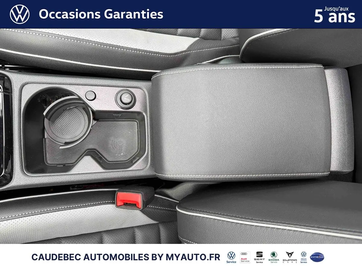 Vue rapprochée de la console centrale avec accoudoir en cuir noir et porte-gobelet de la Volkswagen Golf 1.5 eHybrid blanche 2025.