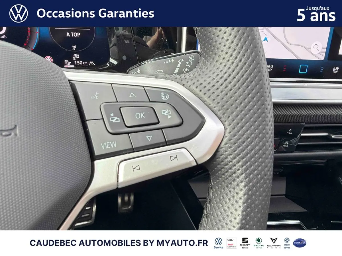 Gros plan sur le volant sport multifonction en cuir perforé de la Volkswagen Golf 1.5 eHybrid blanche, avec commandes intégrées.