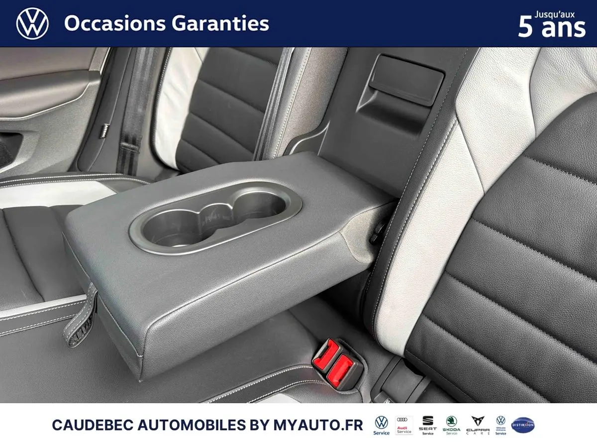 Détail de l'accoudoir central arrière avec porte-gobelets sur sellerie cuir bicolore noir et blanc de Volkswagen Golf 1.5 eHybrid 2025.