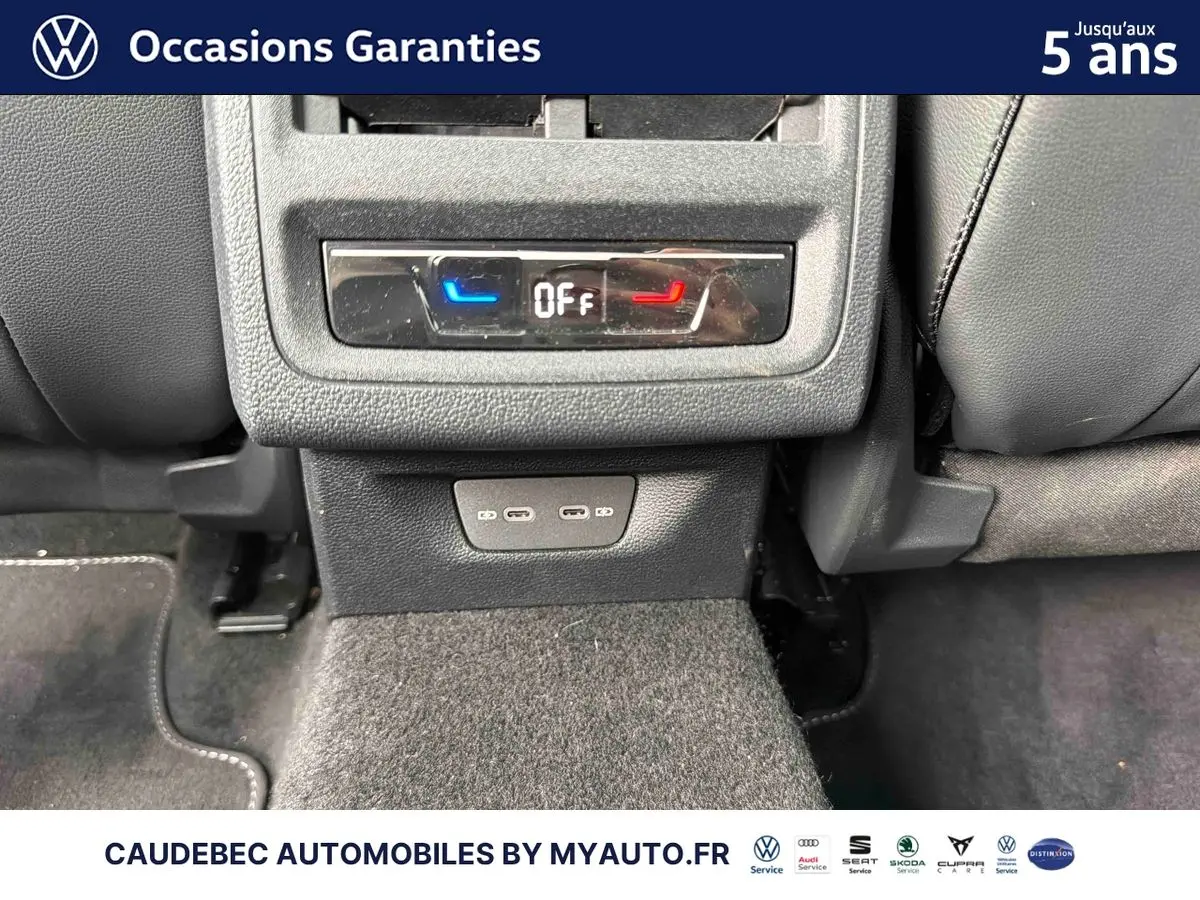 Vue rapprochée de la console arrière d'une Volkswagen Golf blanche, montrant les commandes de climatisation et ports USB.
