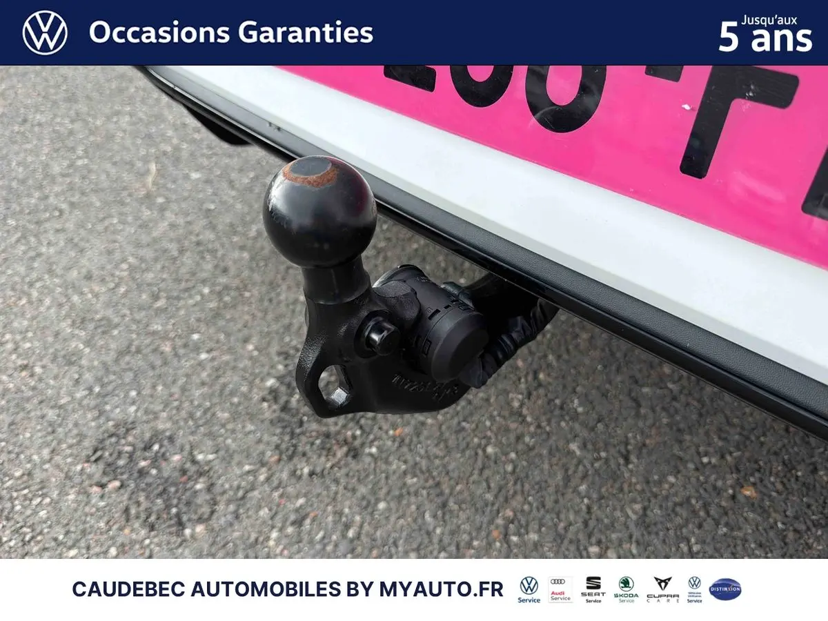 Gros plan sur l'attelage escamotable noir sous le pare-chocs arrière blanc d'une Volkswagen Golf 2025.