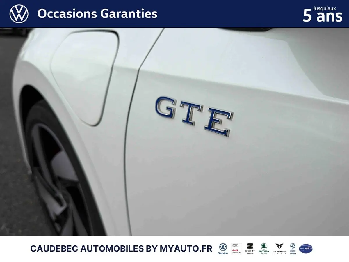 Gros plan sur l'aile arrière gauche blanche d'une Volkswagen Golf 1.5 eHybrid 272 DSG6 avec logo GTE bleu.