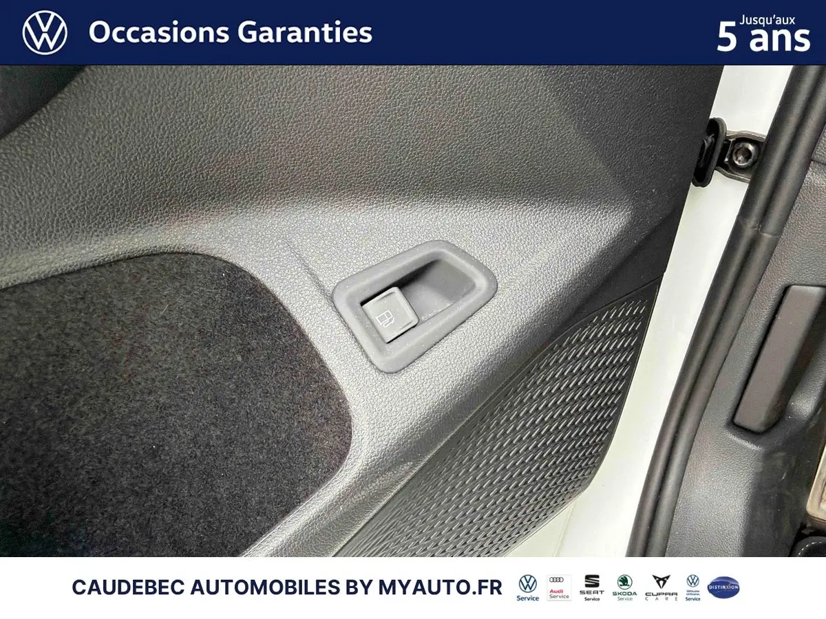 Détail de la porte côté conducteur d’une Volkswagen Golf 1.5 eHybrid blanche, montrant la commande d’ouverture du réservoir.