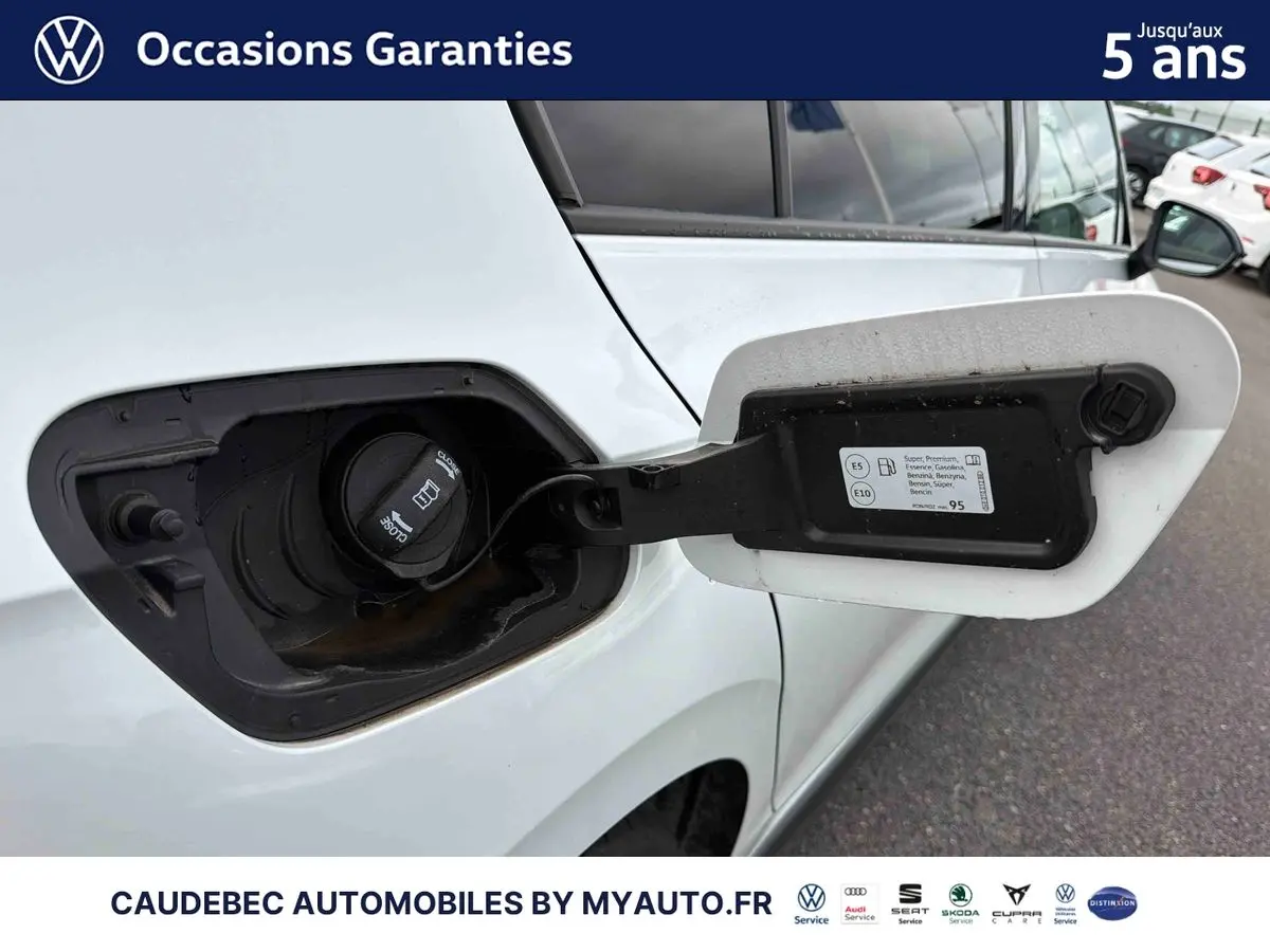 Gros plan sur la trappe à carburant ouverte côté gauche d’une Volkswagen Golf 1.5 eHybrid blanche, avec bouchon visible.