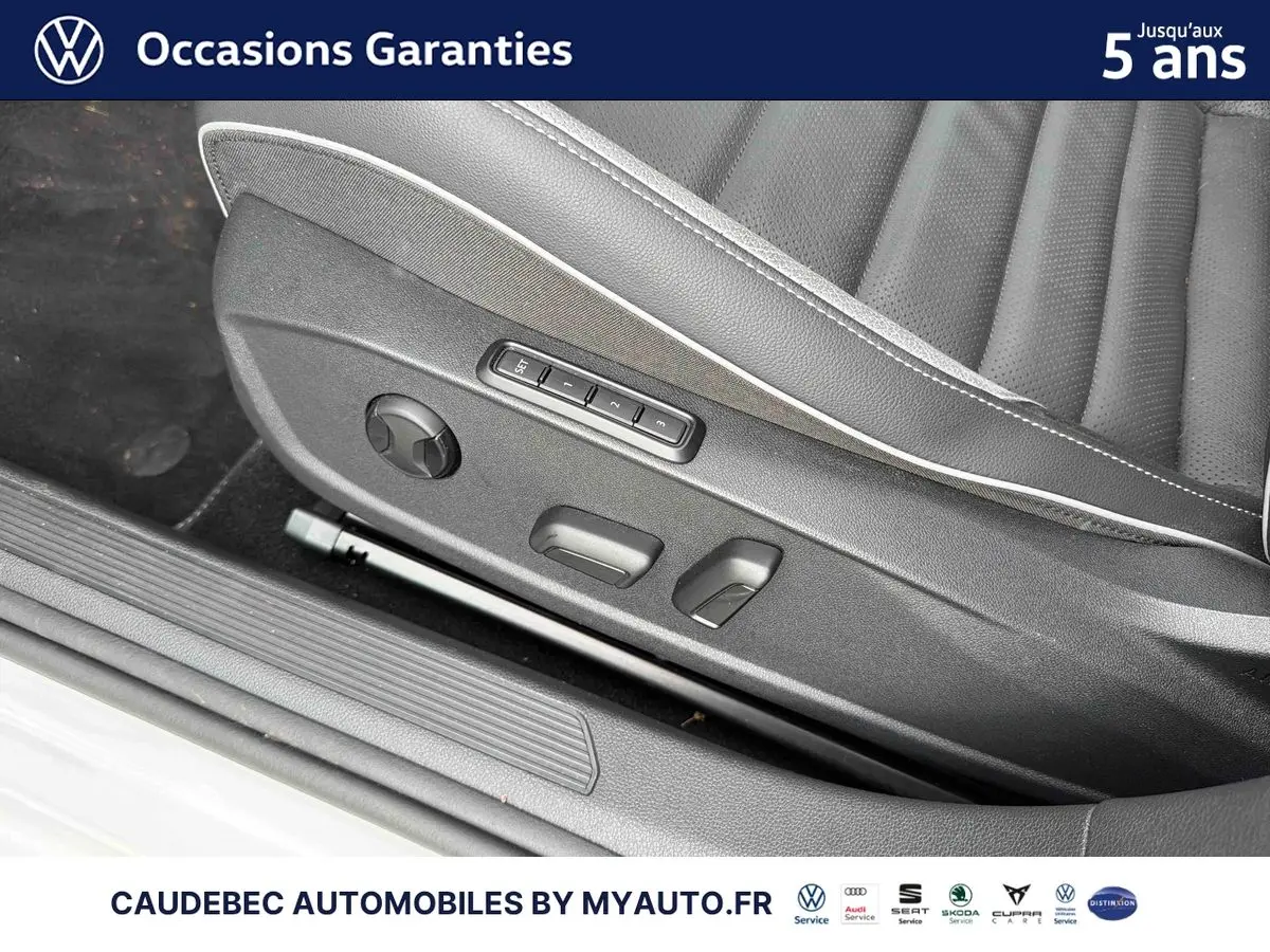 Détail du siège conducteur en cuir noir avec commandes électriques et réglages mémoire dans une Volkswagen Golf blanche.