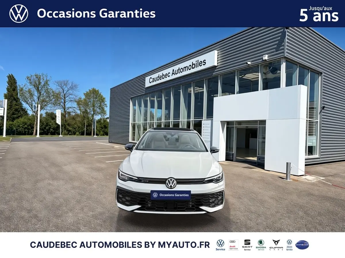 Volkswagen Golf 1.5 eHybrid 272 DSG6 blanche vue de face devant un showroom Caudebec Automobiles.