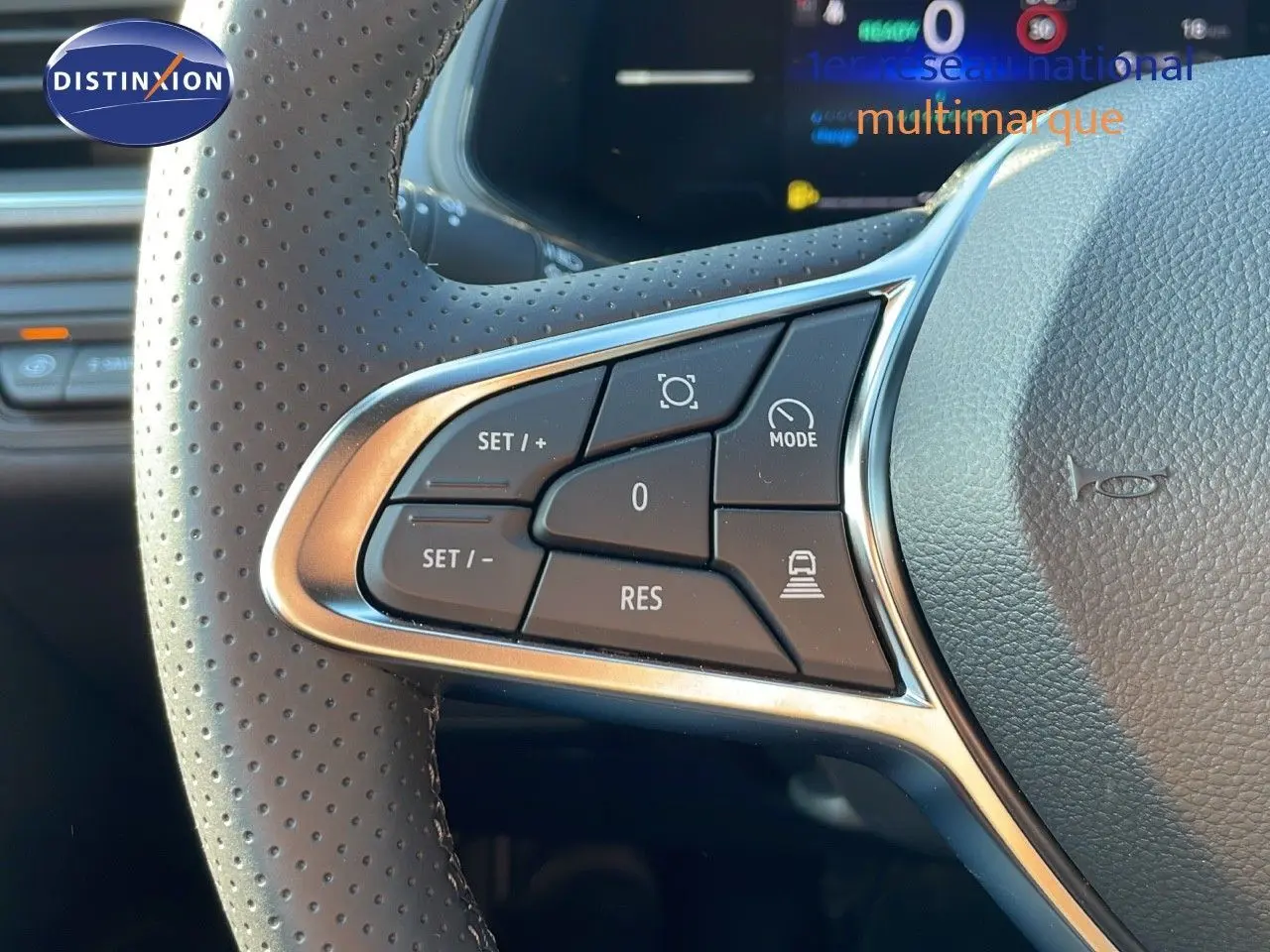 Gros plan sur les commandes au volant perforé du Renault Captur blanc nacré toit gris, version hybride 2025.