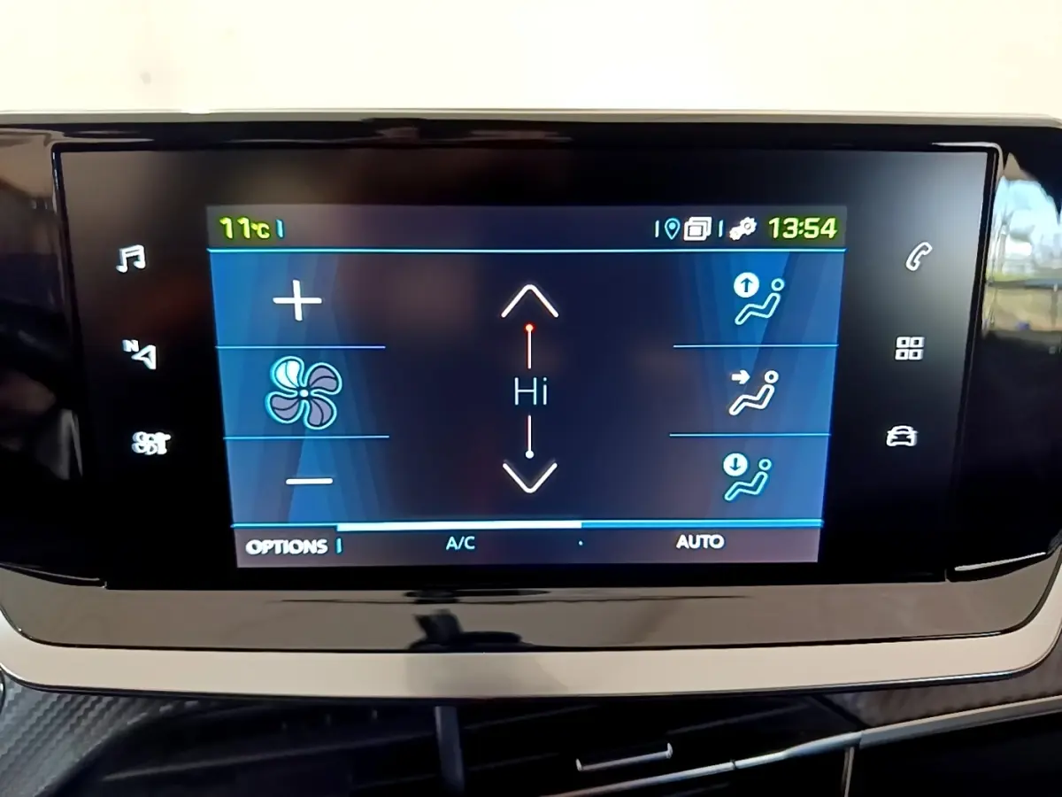 Écran tactile central affichant le réglage de la climatisation dans une Peugeot 208 électrique blanche, vue de face.