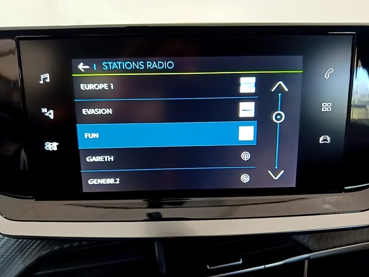 Écran tactile central affichant les stations radio dans l’habitacle d’une Peugeot 208 électrique blanche.