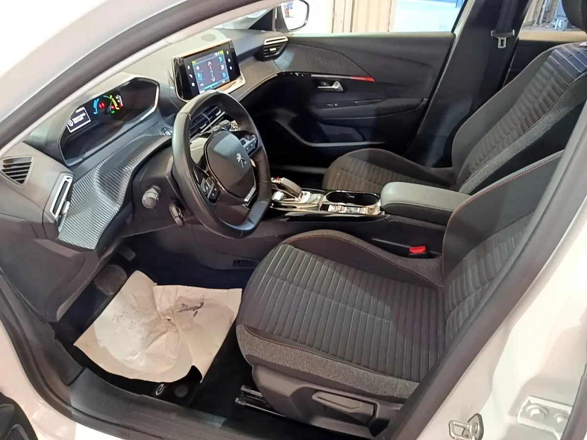 Intérieur avant droit de la Peugeot 208 Electrique Active Business 2021, sièges gris et volant cuir multifonctions.