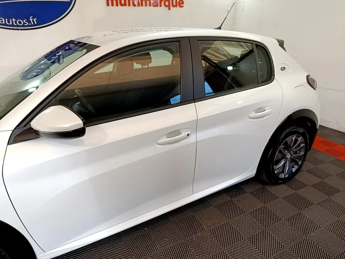 Vue latérale droite d'une Peugeot 208 électrique Active Business blanche, avec jantes alliage et rétroviseurs assortis.