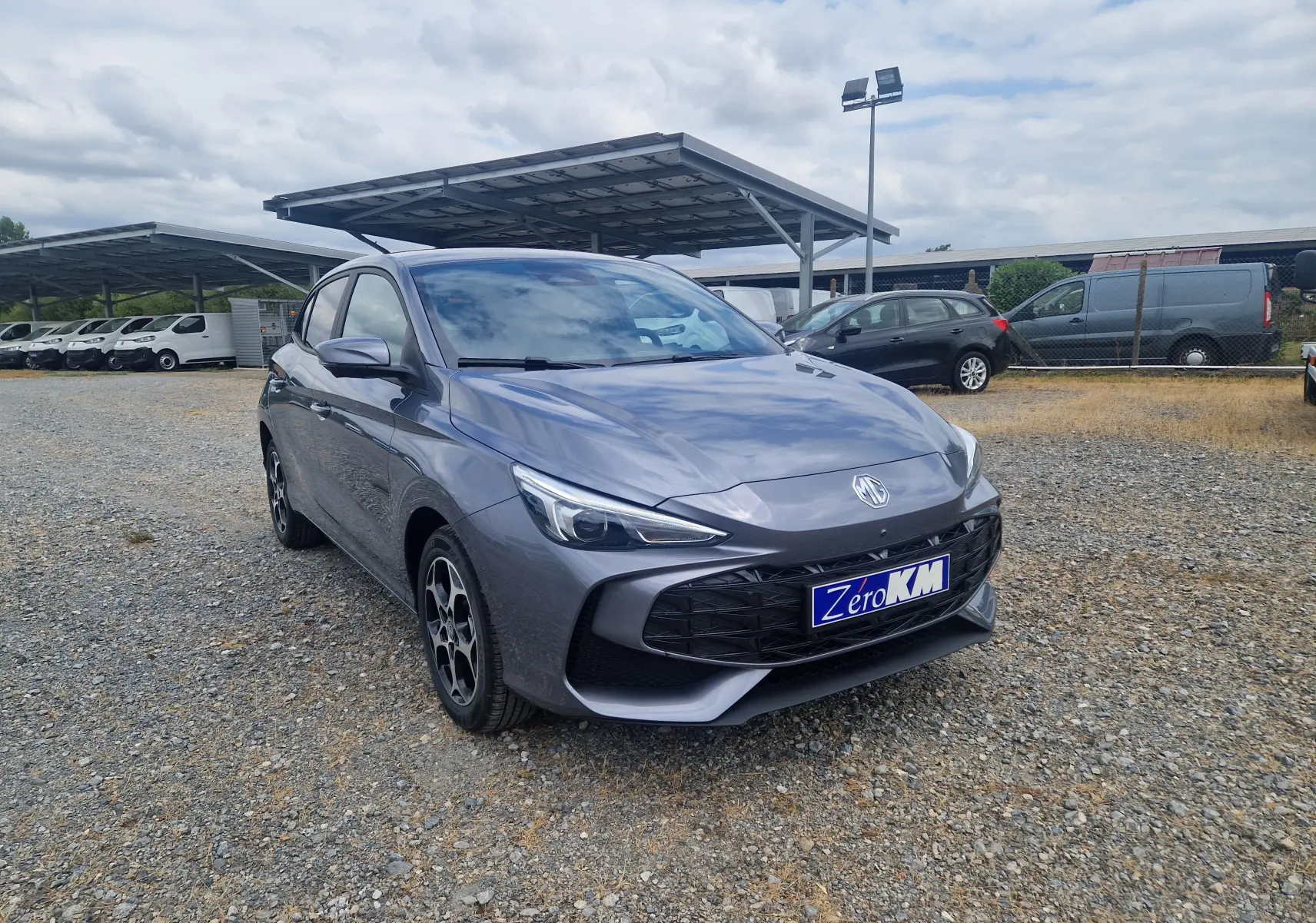 Vue 3/4 avant droite d'une MG3 1.5L Hybrid+ 195ch Luxury gris Hampstead, avec calandre noire et jantes stylées.