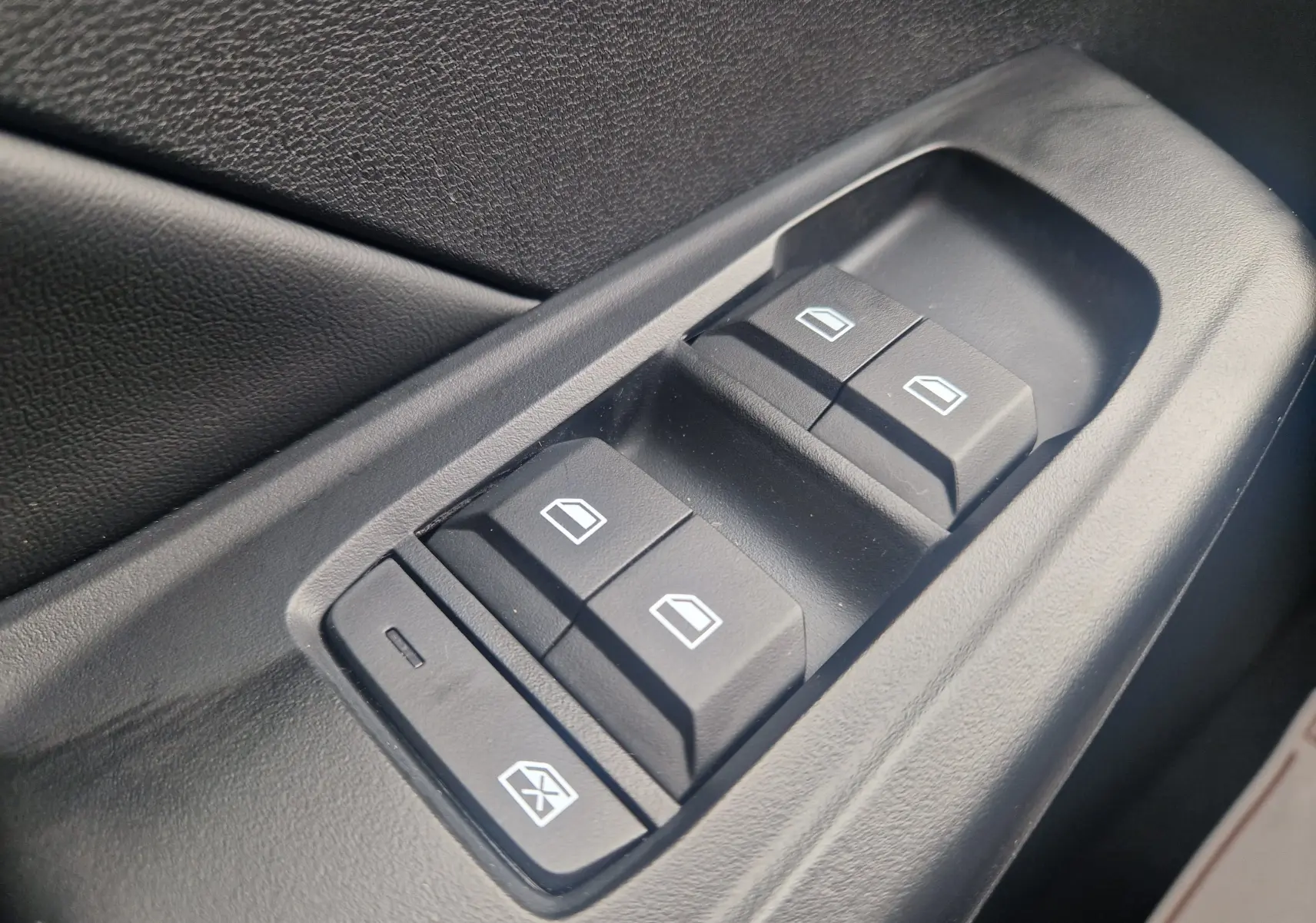 Gros plan sur les commandes de lève-vitres électriques noires côté conducteur d’un MG3 1.5L Hybrid+ 2026 en Hampstead Grey Metal.