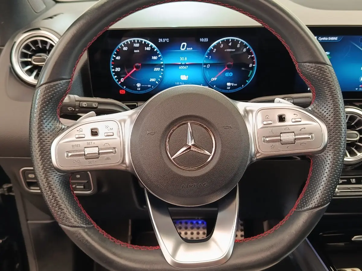 Vue rapprochée du volant cuir noir avec surpiqûres rouges et tableau de bord numérique du Mercedes GLA 250 e AMG Line 2021.
