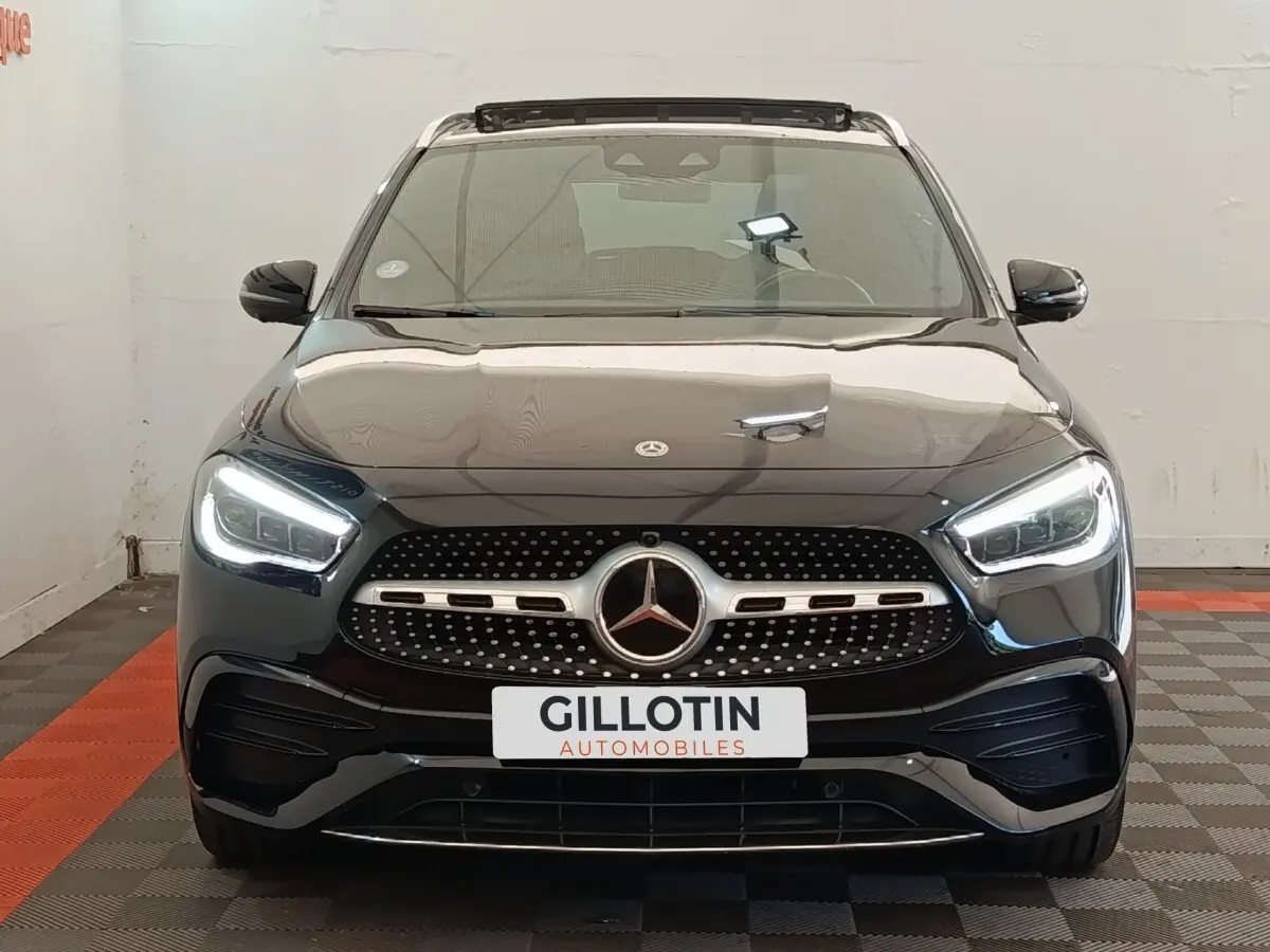 Vue avant d'un Mercedes GLA 250 e AMG Line noir avec phares LED allumés dans un showroom.