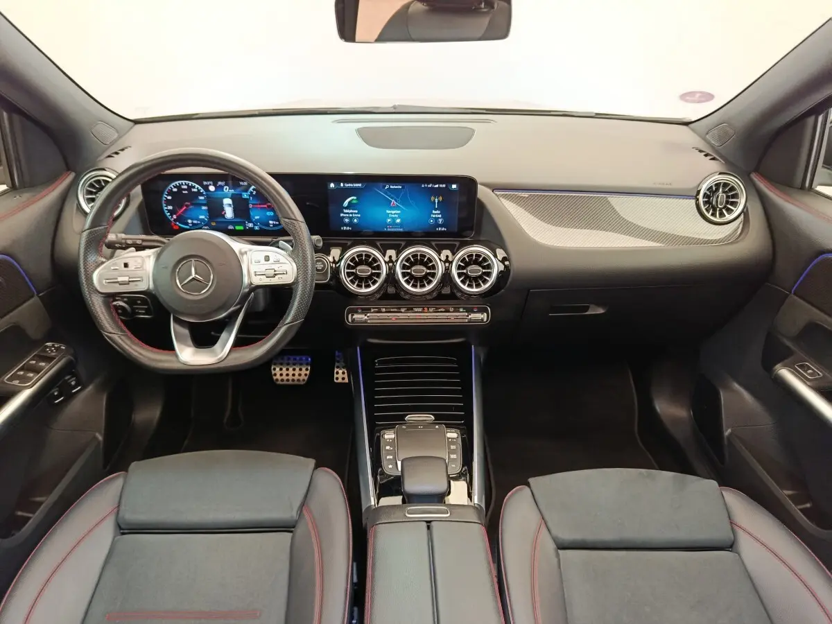 Vue intérieure avant du Mercedes GLA 250 e AMG Line 2021, tableau de bord noir avec écrans numériques et volant cuir.