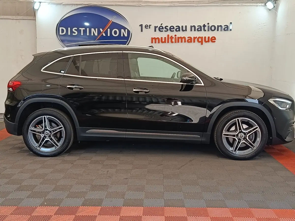 Vue latérale droite d'un Mercedes GLA 250 e AMG Line noir, avec jantes alliage et vitres teintées, en intérieur showroom.