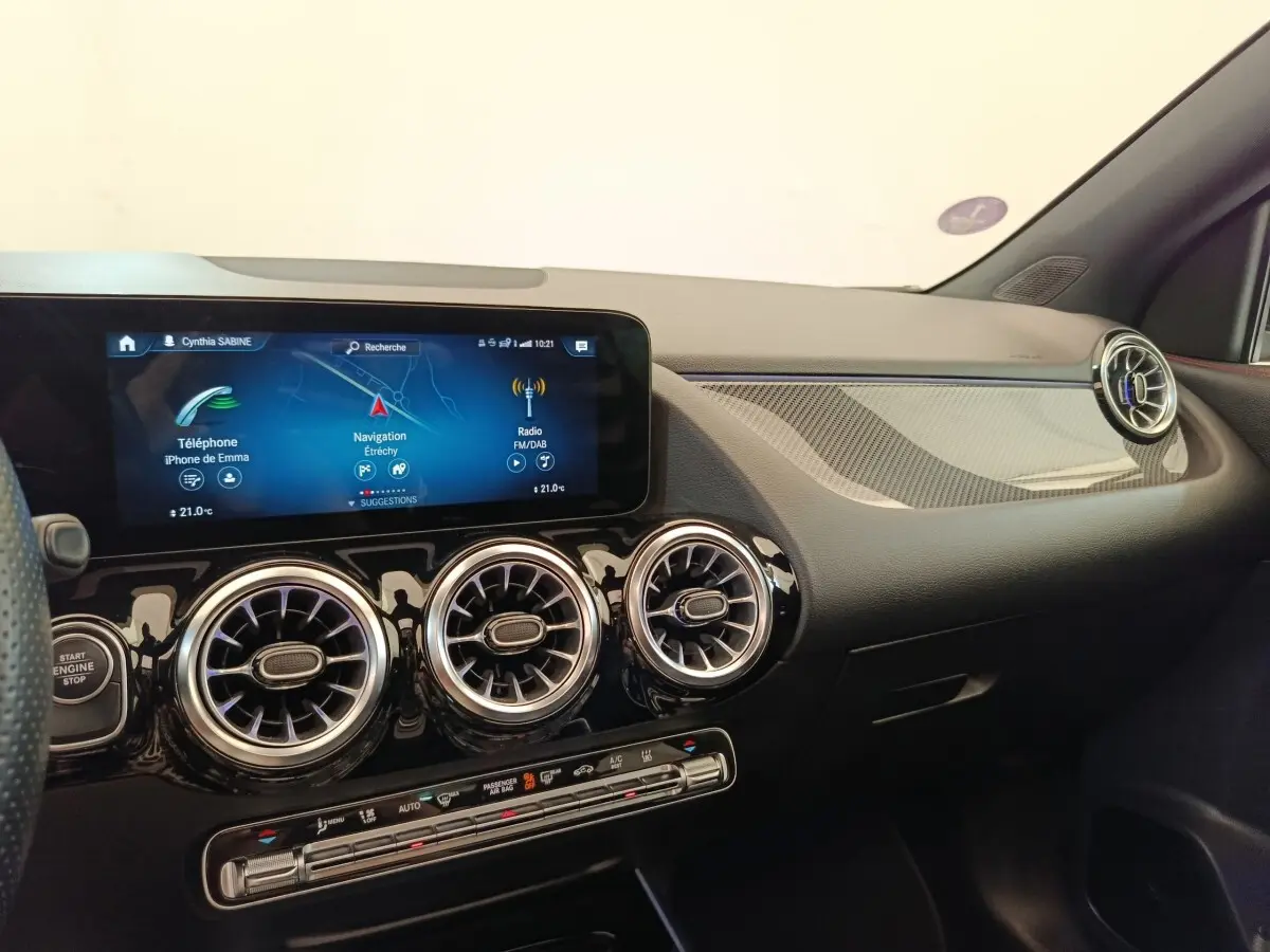 Vue intérieure côté passager du tableau de bord noir du Mercedes GLA 250 e AMG Line avec écran tactile et aérateurs ronds chromés.