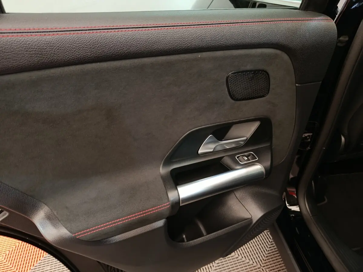Gros plan sur la porte arrière droite noire du Mercedes GLA 250 e AMG Line 2021 avec surpiqûres rouges et poignée alu.